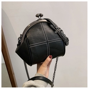 Detail of black shell bag with white cross stitching and metal kiss-lock closure