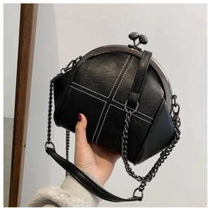 Detail of vintage black shell bag with white cross stitching and metal chain strap