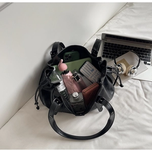 Vue détaillée de la grande capacité du sac seau noir minimaliste avec ses objets quotidiens