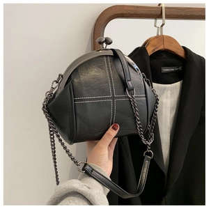 Detail of black shell bag with white stitching and vintage metal clasp closure