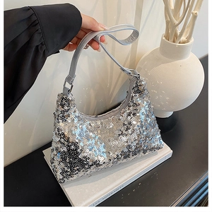 Detail of silver sequin crescent shoulder bag showing reflective texture and leather strap