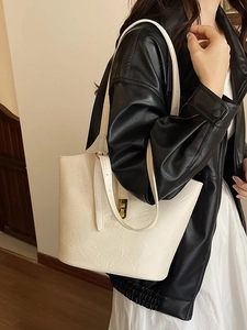 Minimalist ivory leather tote bag with gold lock buckle and adjustable shoulder strap