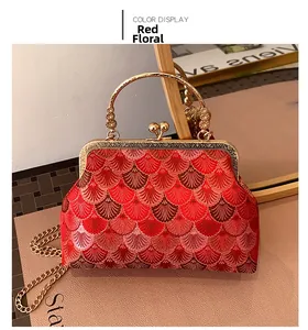 Detail of red floral embroidery on vintage clutch with gold handle and metal chain