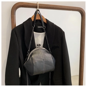 Detail of vintage black shell bag with white cross-stitching and pearl metal clasp