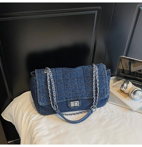 Detail of blue quilted denim shoulder bag with silver turn-lock and chain strap