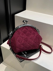 Retro burgundy quilted chain bag with vintage kiss-lock clasp on geometric display stand