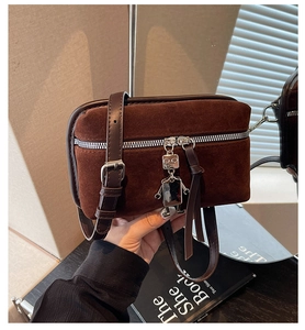 Detailed close-up of dark brown suede crossbody bag with unique silver robot charm