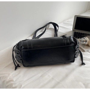 Détail du sac seau en cuir PU noir avec des cordons de serrage élégants sur le côté