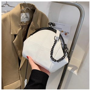 Detail view of white shell bag with lychee texture leather and black metal chain strap