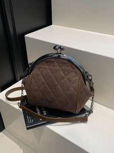 Vintage brown quilted suede kiss-lock crossbody bag with silver chain strap on white steps