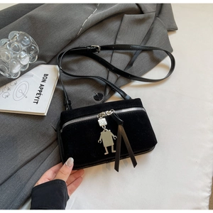 Detail of black suede crossbody bag with a silver robot charm and long zipper strap