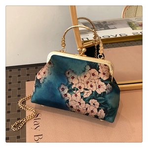 Detail of vintage blue floral handbag with gold metal clasp and intricate handle