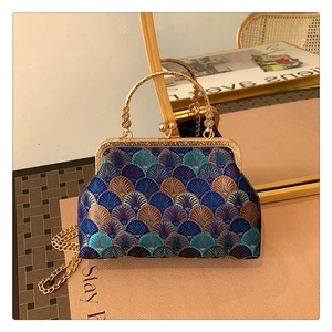 Macro shot of fan-shaped blue embroidery and vintage metal kiss-lock on a retro handbag