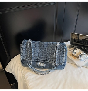 Detail of vintage blue denim quilted handbag with silver chain and metal turn-lock