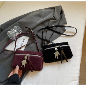 Detail of vintage suede crossbody bags with robot charms and leather tassels in two colors