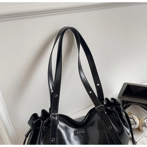 Détail du sac fourre-tout en similicuir noir avec boucles argentées et bandoulières réglables