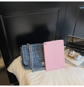 Chic quilted denim crossbody bag with silver chain strap shown in a lifestyle desk setup