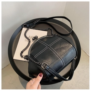 Detail of shell-shaped crossbody bag with white cross-stitching and metal ball clasp
