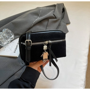 Detail of black suede crossbody bag featuring silver robot charm and metal zipper
