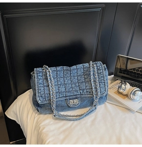 Detail of blue denim chain bag featuring diamond quilted stitching and silver metal buckle