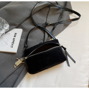 Detail of black suede rectangular crossbody bag with silver hardware and creative pendant