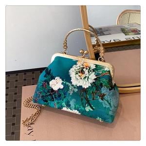 Detailed view of peacock blue floral cheongsam bag with vintage metal clasp and golden handle