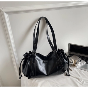 Détail d'un sac en cuir PU noir avec cordon de serrage latéral et garnitures argentées