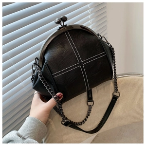 Detail of vintage black shell bag featuring white cross-stitch quilting and metal frame