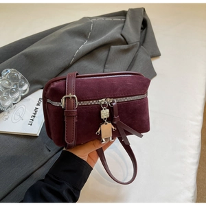 Close-up of suede crossbody box bag in burgundy featuring a unique robot metal charm