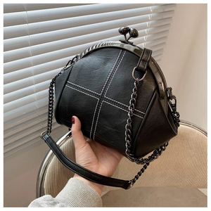 Detail of black shell bag with white cross stitching and vintage metal kiss-lock closure