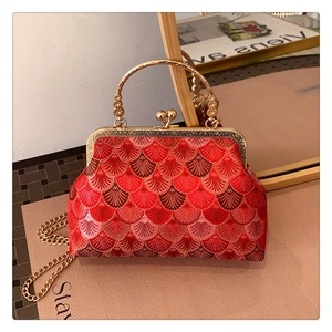 Detailed close-up of red Chinese embroidery on a vintage frame bag with gold ring handle