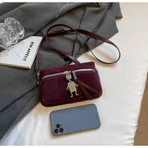 Detail of burgundy suede box bag featuring a silver zipper and metal robot charm