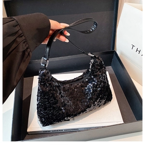 Close-up of black sequined crescent bag inside a gift box with a leather handle