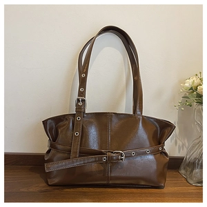 Detailed close-up of dark brown glossy leather shoulder bag with chic pleated design