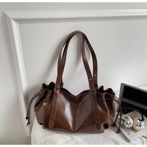 Détail d'un sac cabas en cuir PU marron avec fermeture à cordon et boucles métalliques