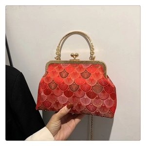 Detail of red Chinese style embroidery handbag with golden metal frame and handle