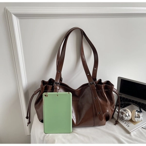 Détail d'un grand sac cabas vintage en similicuir marron avec cordons de serrage latéraux