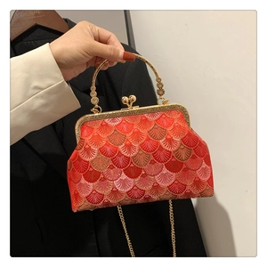 Detail of red vintage silk handbag with golden embroidery and elegant metal clasp