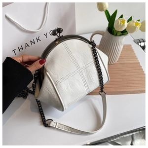 Detailed close-up of white quilted shell bag with black metal clasp and chain strap