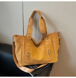 Detail of ginger yellow tote bag featuring side pockets and metal ring buckles