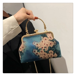 Close-up of vintage floral silk handbag with gold metal clasp and chain strap