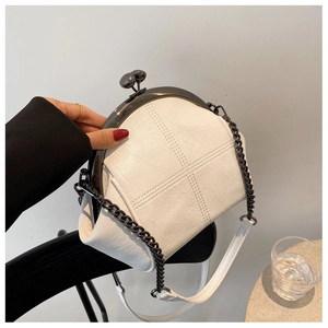 Detail of off-white vintage shell bag featuring cross-stitch and black chain strap