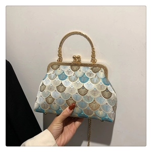 Detailed view of embroidery pattern and metal ring handle on a vintage clasp handbag