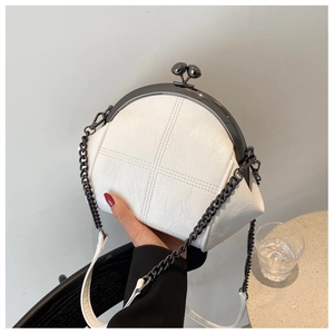 Detail of white quilted shell bag with vintage metal frame and elegant chain strap