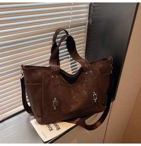Detail of vintage brown tote bag with silver eyelets and side pockets on a windowsill