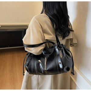 Détail d'un sac à épaule noir en similicuir avec œillets métalliques et cordons