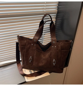 Detail of dark brown tote bag with suede texture, shoulder strap and silver hardware accents