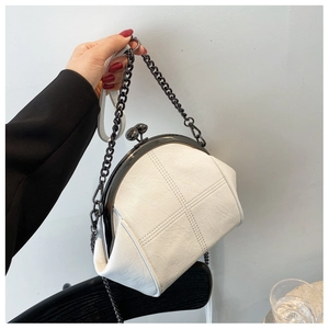 Detail showing the cream shell bag texture with cross-stitch patterns and retro metal clasp