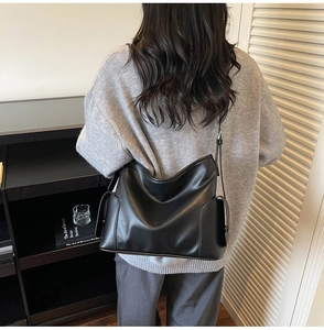 Detail of soft black PU leather tote bag with glossy finish and side buckle pocket detail