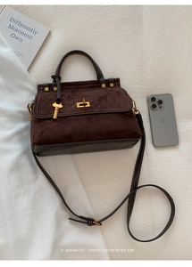 Detailed close-up of a brown matte suede retro handbag with gold hardware and key charm